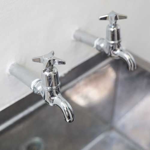 close-up of two taps on a stainless steel sink